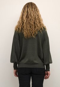 Maglione verde scuro con una vestibilità rilassata, maniche lunghe a palloncino, polsini a coste e un tessuto lavorato. La vista posteriore mostra un orlo arrotondato.