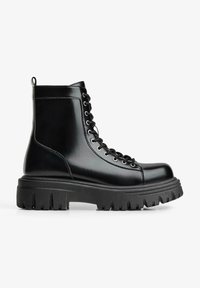 Černé kotníkové boty z kůže s masivní gumovou podrážkou. Mají kulatou špičku, tkaničky a poutko na patě pro snadné obutí. Hladká textura.