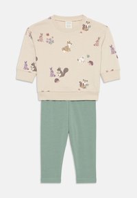 Felpa beige con motivi animali; colletto rotondo, tessuto morbido. Leggings verdi, vita elastica, design aderente, texture liscia.