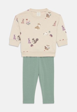 Beige sweatshirt med dyremønstre; rund hals, myk stoff. Grønn leggings, elastisk midje, tettsittende design, glatt tekstur.