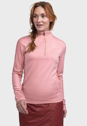 Helles rosa Langarm-Zip-Up-Top mit strukturiertem Design, hohem Kragen und Logodetail; kombiniert mit einem roten gepolsterten Rock.