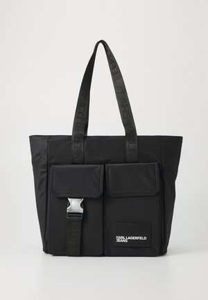 Zwarte tote tas met twee voorvakken, één met een zilveren gesp, en zwarte handvatten met reliëf branding. Wit "Karl Lagerfeld Jeans" logo op het vak.