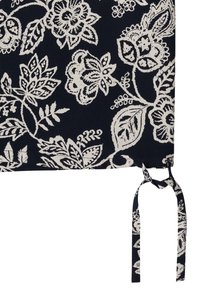 Tissu bleu marine avec des motifs floraux et feuilles blancs, doté d'une sangle en tissu nouée sur le bord.