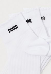 Bijele čarape s rebrastim dizajnom imaju volanasti rub i crni logo "PUMA". Izrađene su od mekanog, elastičnog materijala pogodnog za svakodnevno nošenje.