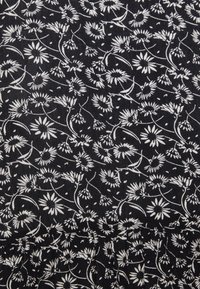 Černá tkanina s květinovým vzorem s bílými sedmikráskami a jemnými stonky. Opakující se vzor pokrývá celý povrch, což vytváří texturu.