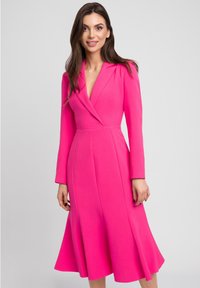 Fuksjowa sukienka z długimi rękawami, głębokim dekoltem w kształcie litery V i rozkloszowanym dołem. Wykonana z fakturowanej tkaniny z detalami szwów przy korpusie i spódnicy.