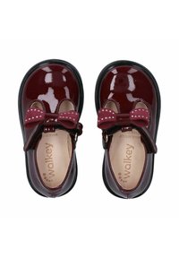 Scarpe in pelle verniciata bordeaux con design Mary Jane, caratterizzate da un rinforzo a fiocco con pois. Suola in gomma nera. Fodera interna morbida.