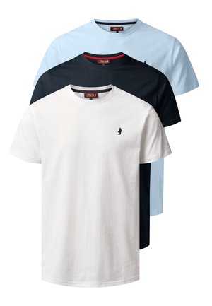 Fiatal férfi, aki egyszerű fehér rövid ujjú pólót visel kis fekete logóval a mellkasán, sötétkék farmerrel párosítva.