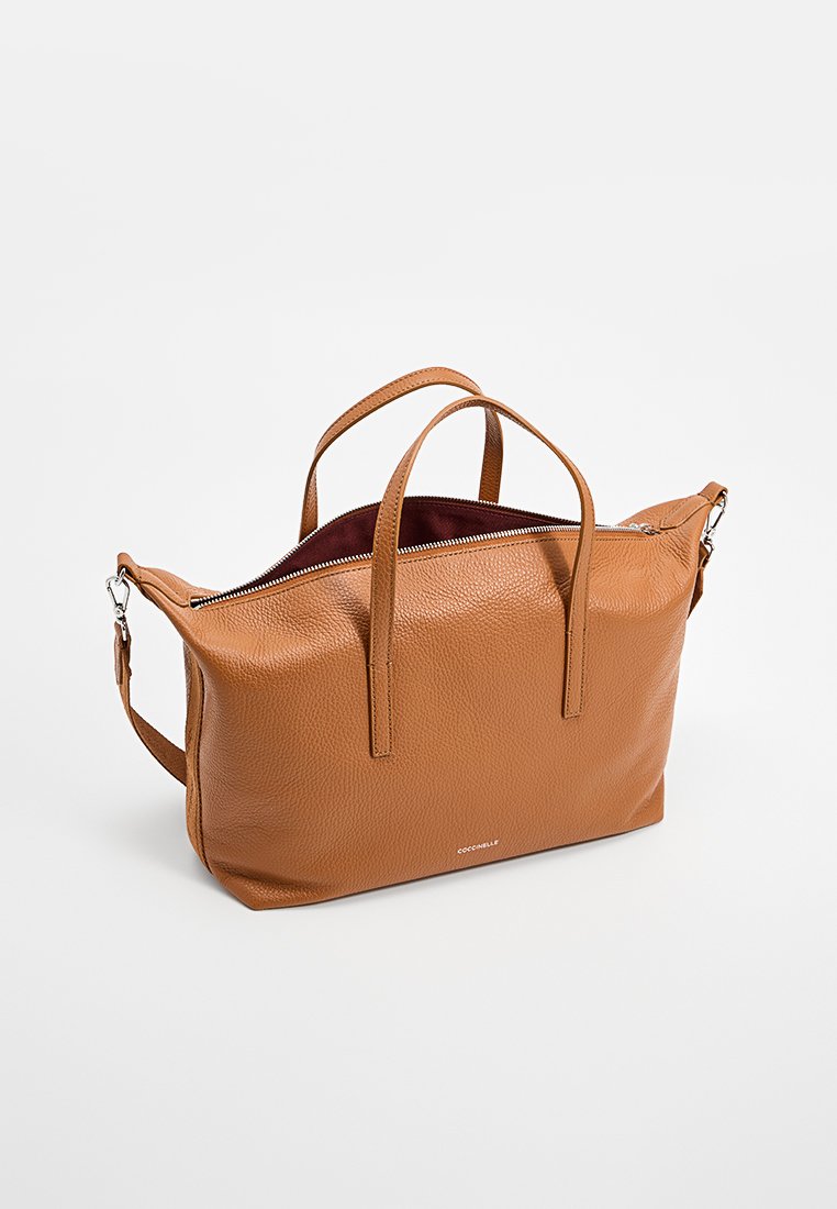 Skórzana torebka w kolorze brązowym z dwoma uchwytami i odpinanym paskiem na ramię. Posiada zamek błyskawiczny oraz kontrastowy kolor wnętrza.