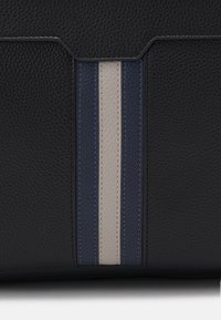 Sac en cuir noir avec une surface texturée, accentué par trois rayures verticales en bleu foncé, gris clair et bleu marine.