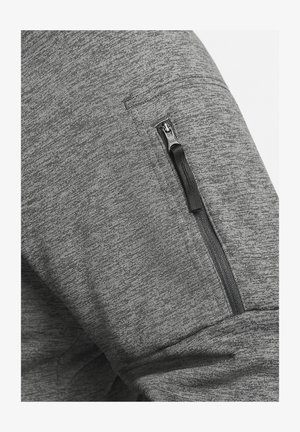 Pilkos sportinės kelnės su užtrauktuku kišenėje šone, pagamintos iš tekstūruotos, elastingos medžiagos, užtikrinančios komfortą ir judrumą.