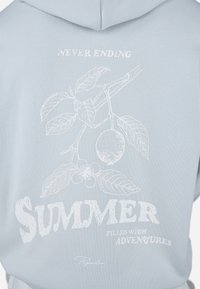 Lyseblå hettegenser med hvit grafisk design av blader, frukt og teksten "ALDRI ENDER SOMMER FYLT MED EVENTYR." Myk tekstur.