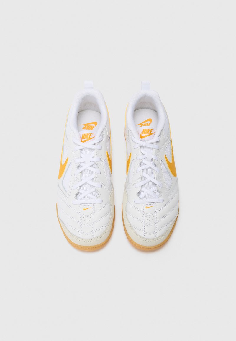 Zapatillas deportivas blancas con acentos naranjas, con un upper suave, superposiciones texturizadas y una suela de goma. Los cordones son blancos.