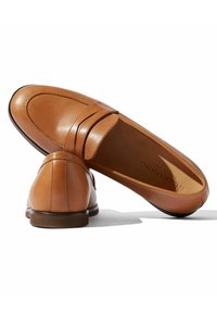 Brune læder loafers med rund tå, penny strap-detalje og lav hæl. Glat tekstur med diskret syning i overdelen.