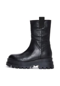 Botín negro de cuero con suela de goma gruesa, que presenta un acabado texturizado, costuras laterales y una lengüeta en la parte posterior.