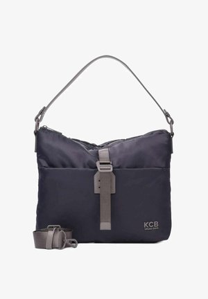 Bolso vegano azul marino con textura acolchada, correa gris ajustable y cierre frontal con correa. Diseño minimalista con un logo.