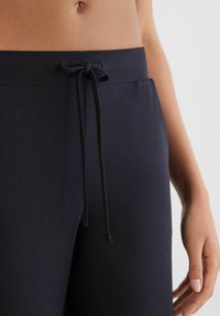 Pantalones joggers en color marino con una tela suave, que cuentan con una cinturilla elástica y un cordón en la parte delantera para un ajuste ajustable. Textura suave, diseño casual.