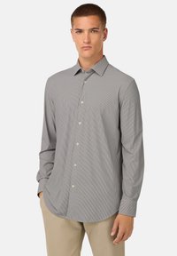 Camicia grigia con bottoni e sottili righe bianche. Presenta un colletto classico, maniche lunghe e orlo arrotondato. Il materiale sembra liscio e leggero.