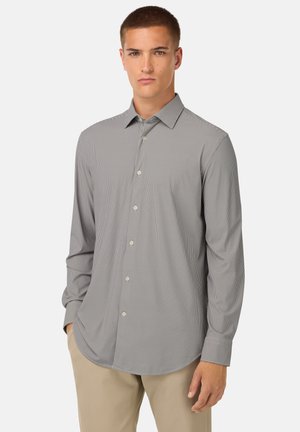 Camisa de botones gris con finas rayas blancas. Presenta un cuello clásico, mangas largas y dobladillo redondeado. El material parece suave y ligero.