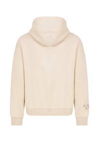 Crème korte hoodie met een ruime capuchon, ribgebreide cuffs en een klein geborduurd tekstdetail op de rechtermanchet. Zachte, gladde textuur.