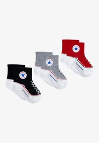 Tres pares de calcetines tobilleros: negros con una suela y logotipo blancos, grises con un diseño similar y rojos con acentos blancos contrastantes.