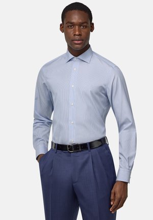 Light blue striped dress shirt with a classic collar, button front, and long sleeves, paired with navy dress trousers and a black belt.