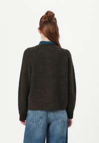 Brown, textured sweater with a crew neck and drop shoulders, paired with light blue wide-leg jeans. Wool blend material, casual fit.