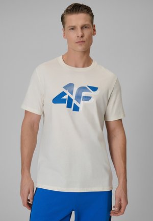 Mężczyzna ubrany w białą koszulkę z niebieskim logo "4F" oraz jasnoniebieskie spodenki, stojący na jednolitym szarym tle.