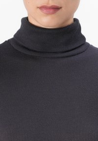 Svart, rilletrøye med høy hals og tettsittende design, med en glatt tekstur.