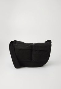 Borsa a tracolla in velluto a coste nero con due tasche frontali con patta e una tracolla regolabile su uno sfondo chiaro uniforme.