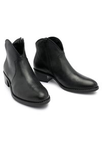 Par de botas negras de cuero hasta el tobillo con cremalleras laterales y tacones bajos, mostradas contra un fondo blanco.