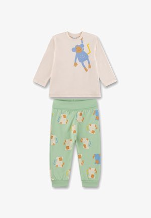 Langärmliges cremefarbenes Hemd mit blauer Affen-Grafik, kombiniert mit grüner Jogginghose, die wiederholt Affenmuster in gedämpften Farben zeigt.