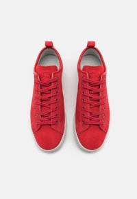 Zapatillas de gamuza roja con textura suave, que cuentan con cordones redondos, una lengüeta de talón con lazo y un diseño minimalista, con una suela de goma gris.