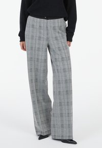 Gray plaid wide-leg trousers with a check pattern, featuring a smooth finish and button closure at the waist. Styled with a black top.