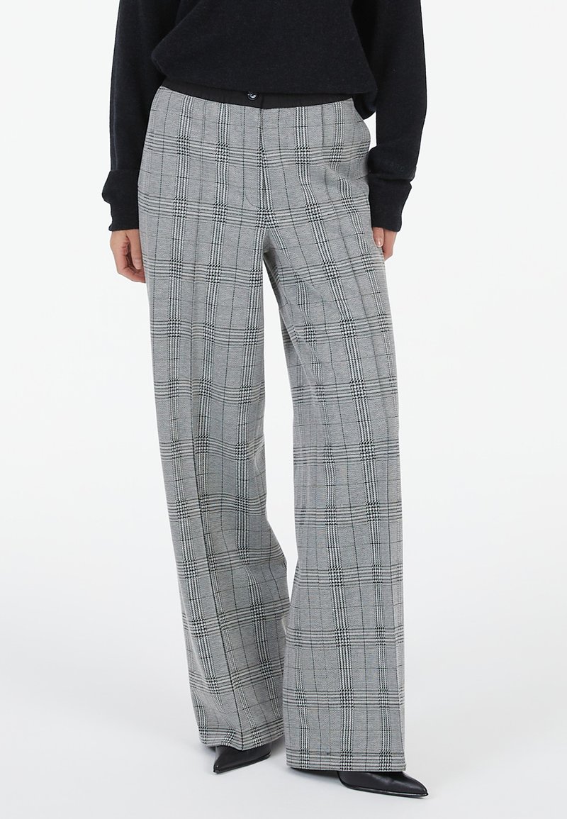 Gray plaid wide-leg trousers with a check pattern, featuring a smooth finish and button closure at the waist. Styled with a black top.