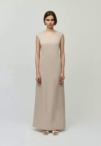 Beige sleeveless midi dress with a straight silhouette, smooth texture, and minimalist design. Features a high neckline and floor-length style.