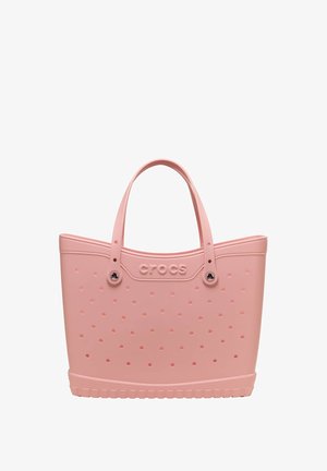 Roze Crocs draagtas met geperforeerde gaten, twee handvatten en een gestructureerde basis.