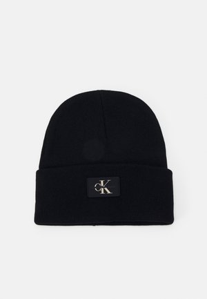 Zwart gebreide muts met omgeslagen boord met een klein rechthoekig label met het "cK" Calvin Klein-logo in lichte letters.