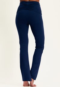 Marineblaue, enganliegende Leggings mit einem hohen, gerafften Bündchen und ausgestellten Hosenbeinen. Hergestellt aus dehnbarem Stoff für Komfort und Bewegungsfreiheit.
