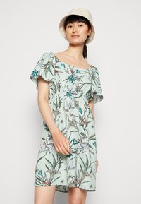 Vestido curto floral em verde claro, com um decote largo, mangas soltas e uma cintura ajustada, adornado com padrões de borboletas e flores.