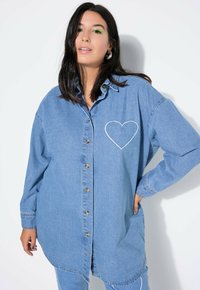 Lichtblauwe denimshirt met een geborduurde hartomtrek op de linkerkant van de borst, knoopsluiting aan de voorkant en lange mouwen met een gebogen zoom.