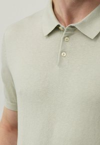 Jasnozielona krótka koszulka polo z miękką fakturą, z trzema guzikami i klasycznym kołnierzykiem. Minimalistyczny design bez wzorów.