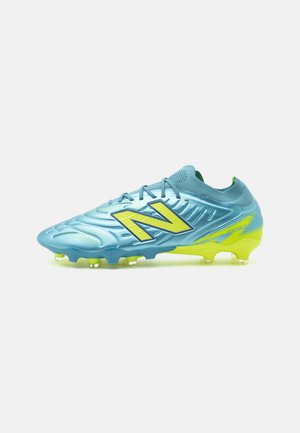 Blå og gule New Balance fodboldstøvler med snørebånd og knot sål, vendt mod venstre på hvid baggrund.