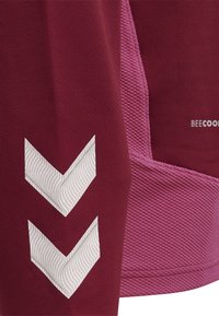 Bordeauxfarbener Stoff mit zwei weißen Chevron-Streifen und einem rosa strukturierten Paneel in der Nähe, mit kleinem Text "BEECOOL".