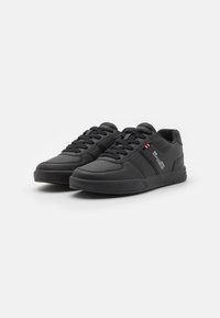 Black athletic shoes featuring smooth synthetic leather, round toe, lace-up design, perforated accents, and a textured rubber sole.
