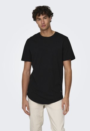 Black short-sleeve t-shirt made of cotton, featuring a round neckline and a curved hem, worn with light-colored pants.