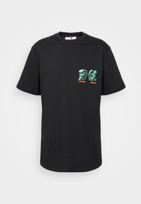 Black cotton t-shirt featuring short sleeves, a crew neckline, and two green graphic designs with "VERTERE" and "BERLIN" text.