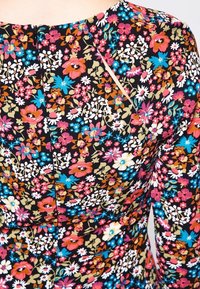 Floral dress with a black background, featuring colorful pink, blue, and white flowers, a fitted shape, and a back zipper detail.