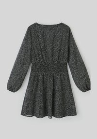 Robe noire avec des taches blanches, manches longues bouffantes, et taille élastique. Texture fluide et forme en A avec un décolleté arrondi.