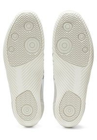 White shoe soles with circular patterns, textured herringbone grip, and rounded accents. Flat profile with no visible logos or branding.